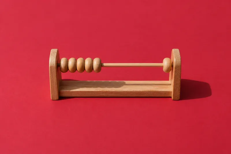 A small wooden abacus with one row of beads, one bead slid across, on cherry-red paper.