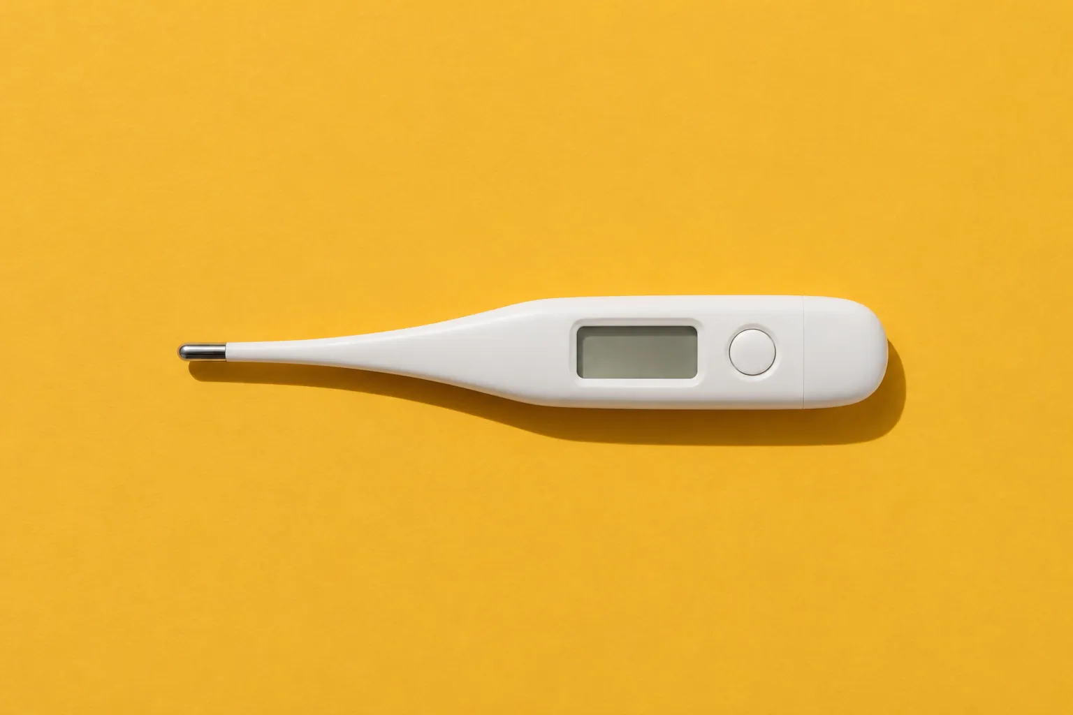 A white digital thermometer with a blank screen on mustard-yellow paper.