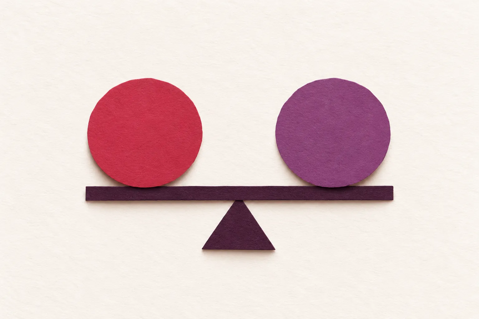A cherry paper circle and a plum paper circle balanced on an aubergine beam, on cream paper.