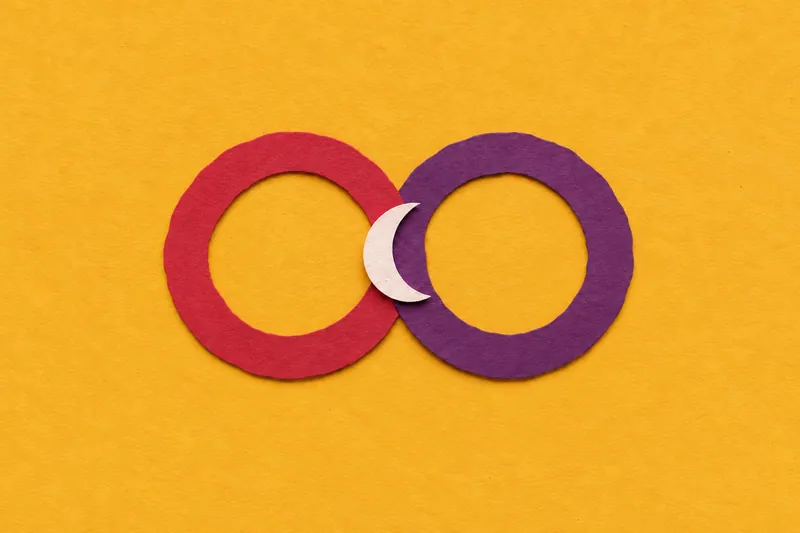 Two cut-paper rings, one cherry and one plum, overlapping on mustard paper, with a small cream crescent between them.