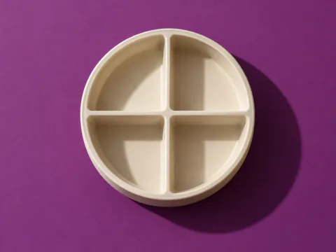 A cream ceramic dish divided into four, on plum paper.